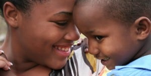 Picture of a young girl holding a toddler, both smiling